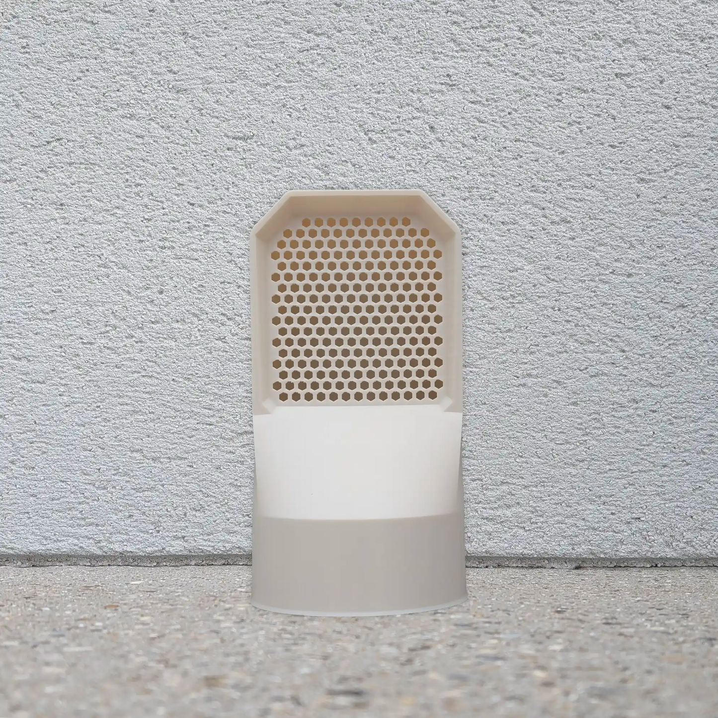 Mise en situation d'une grille d'aération couleur beige installée au sol pour la ventilation extérieure d'une maison.