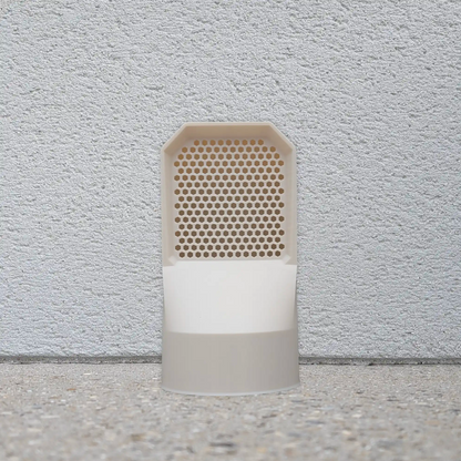 Mise en situation d'une grille d'aération couleur beige installée au sol pour la ventilation extérieure d'une maison.